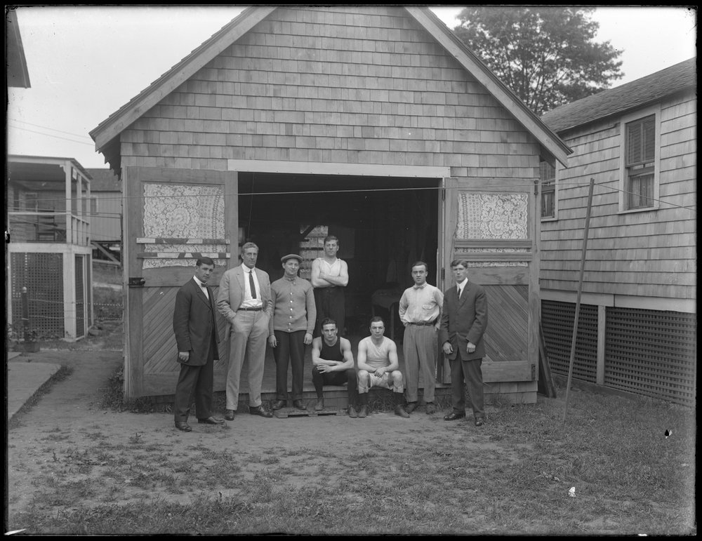Gruppeportrett av den engelske bokseren William Thomas Wells (Bombardier Billy Wells), Jim Maloney, Syd og andre uidentifiserte følgesvenner (Brown), stående foran en uidentifisert garasje, ca. 1911 av William Davis Hassler
