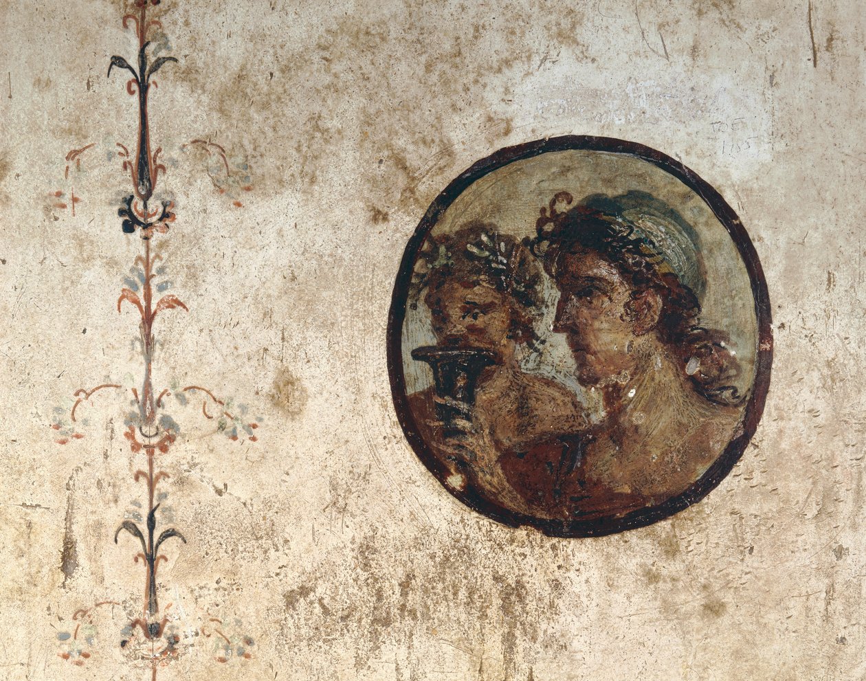 Interiør i et rom med veggfresker fra romertiden, stil III, i huset til Corieo Tiburtino i Pompeii: en del av en vintreet og en tondo med to mannlige hoder av Unknown