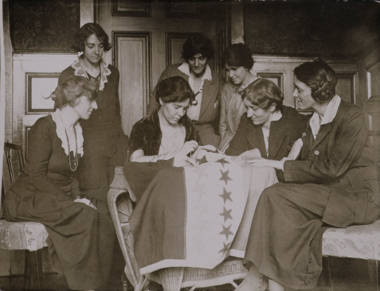 Alice Paul syr stjerner på stemmerettsflagget mens andre kvinner ser på, ca. 1920 av American Photographer