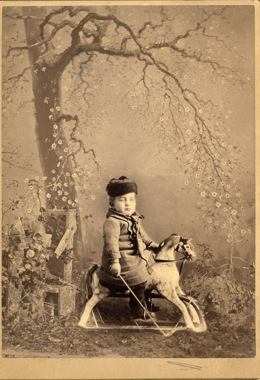 Ung gutt satt på en gyngehest med stort malt bakteppe, 1880-tallet (albumintrykk) av American Photographer