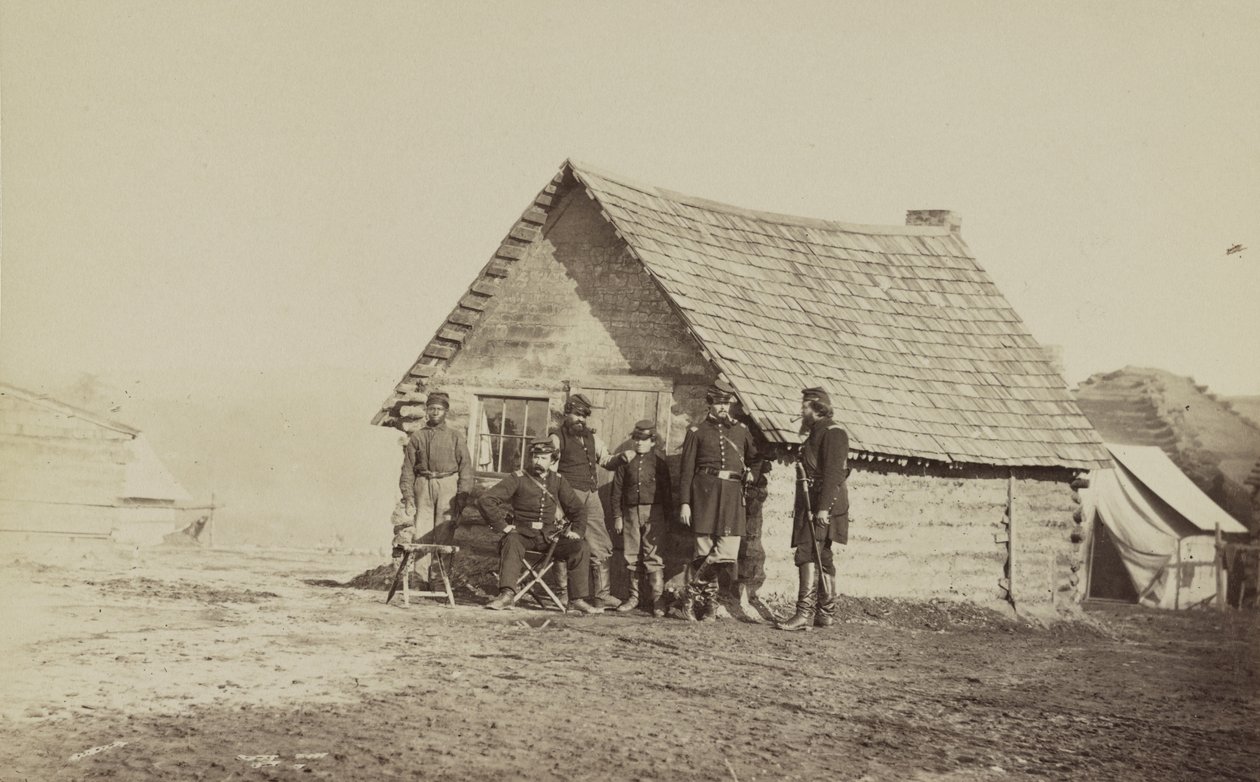 En gruppe soldater og to unge menn, en afroamerikaner, står utenfor tømmerhyttekvarteret, 1861-65 av American Photographer