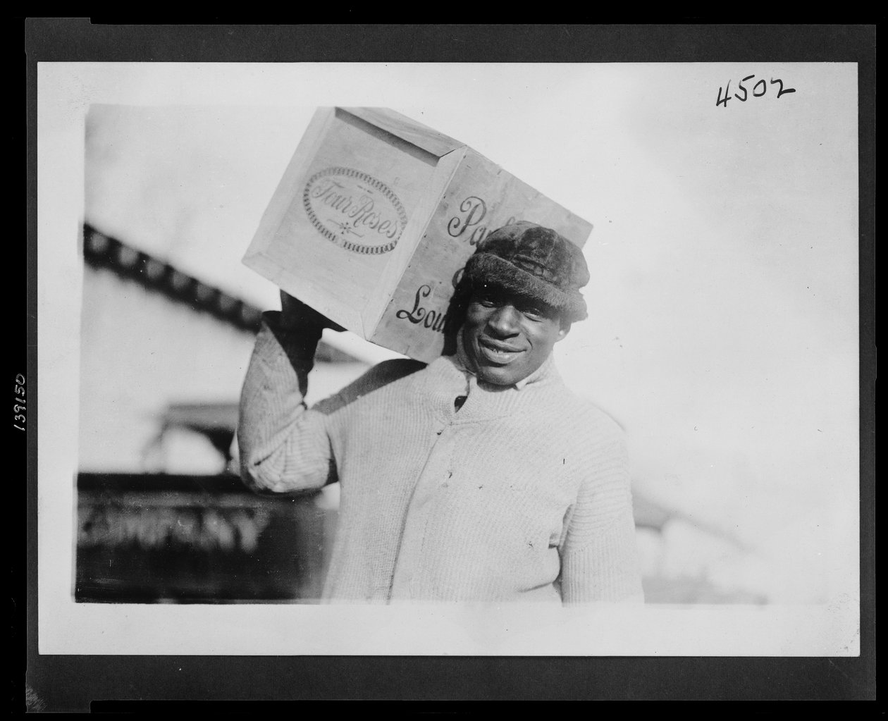 Afroamerikansk mann bærer et etui med "Four Roses" whisky på skulderen, muligens konfiskert av US Internal Revenue Bureau av American Photographer