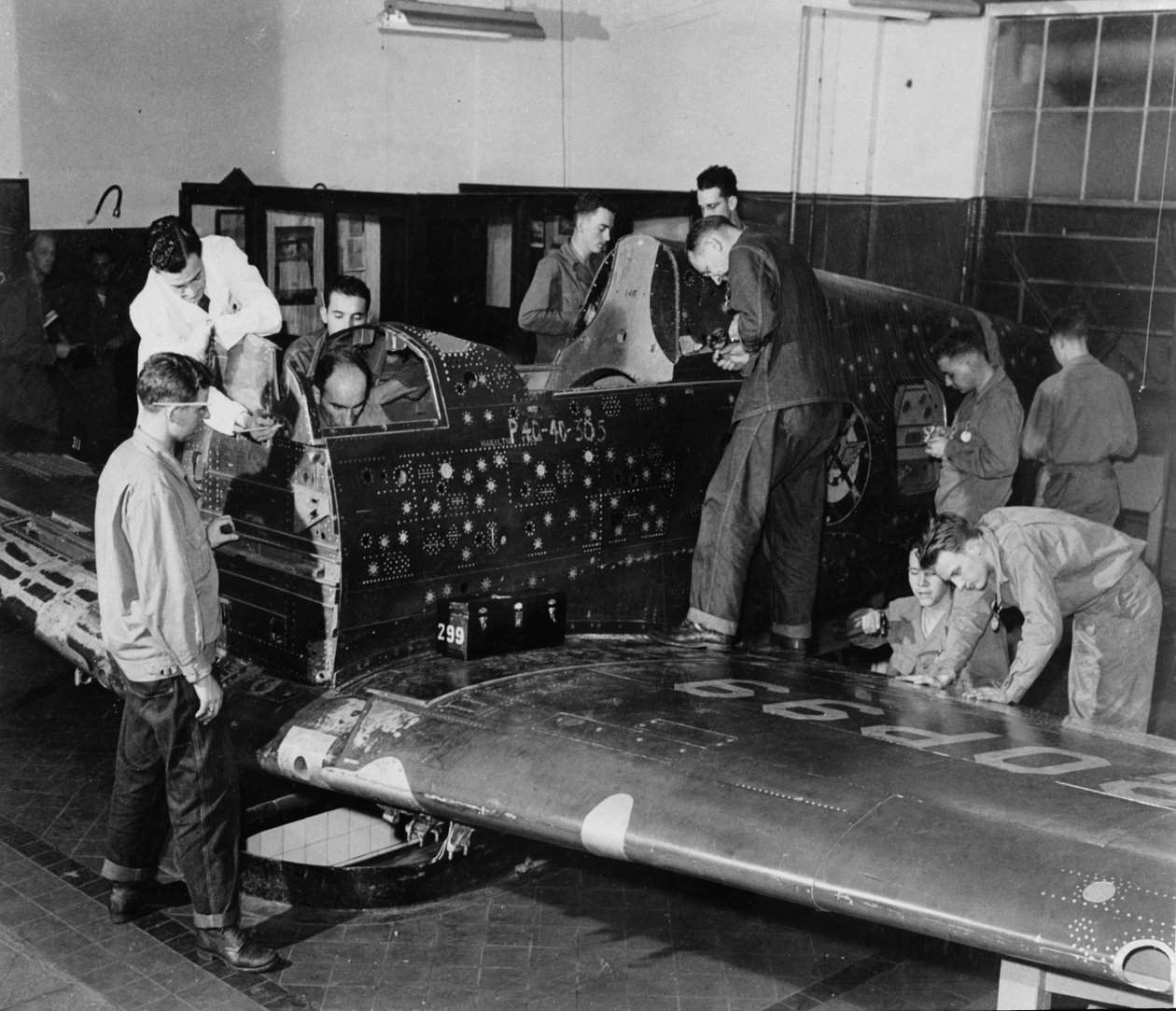 Soldatelever jobber på "Flying Patch", et Curtiss "Warhawk" jagerfly uten motor eller halemontering, med simulerte kulehull og lapper, ca. 1942 av American Photographer