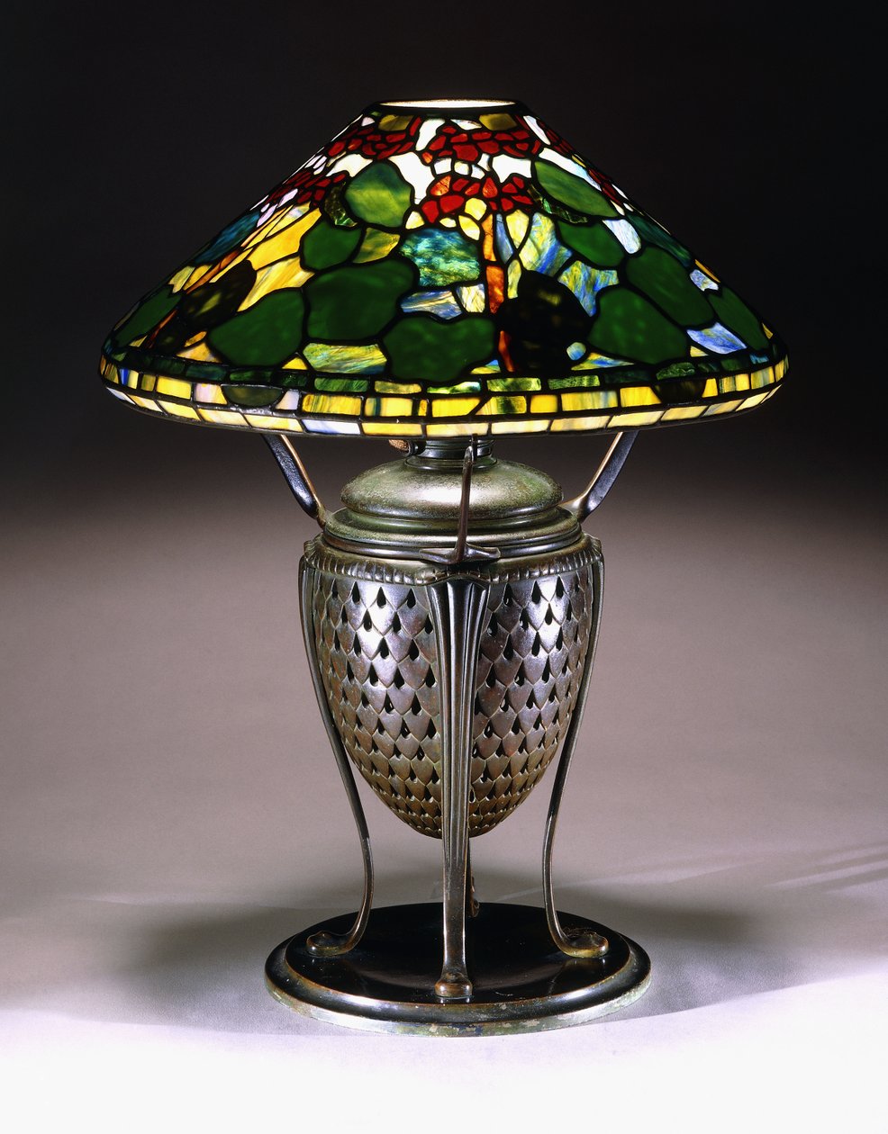 En "Geranium" bordlampe med en konisk skjerm og nettformet urnebase i bronse med fiskeskjellmønster, 1900-tallet av American School
