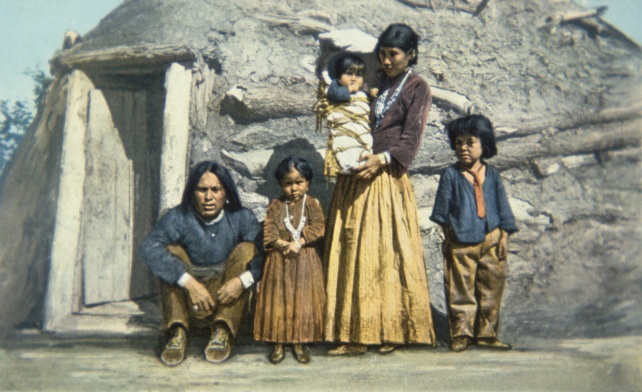 Postkort av en indisk familie fra Navajo utenfor huset deres eller "hogan" av American School