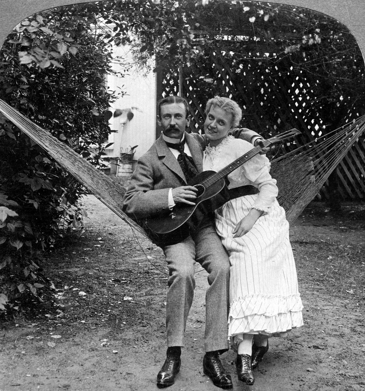 Det musikalske paret i hengekøyen. av American Stereoscopic Company