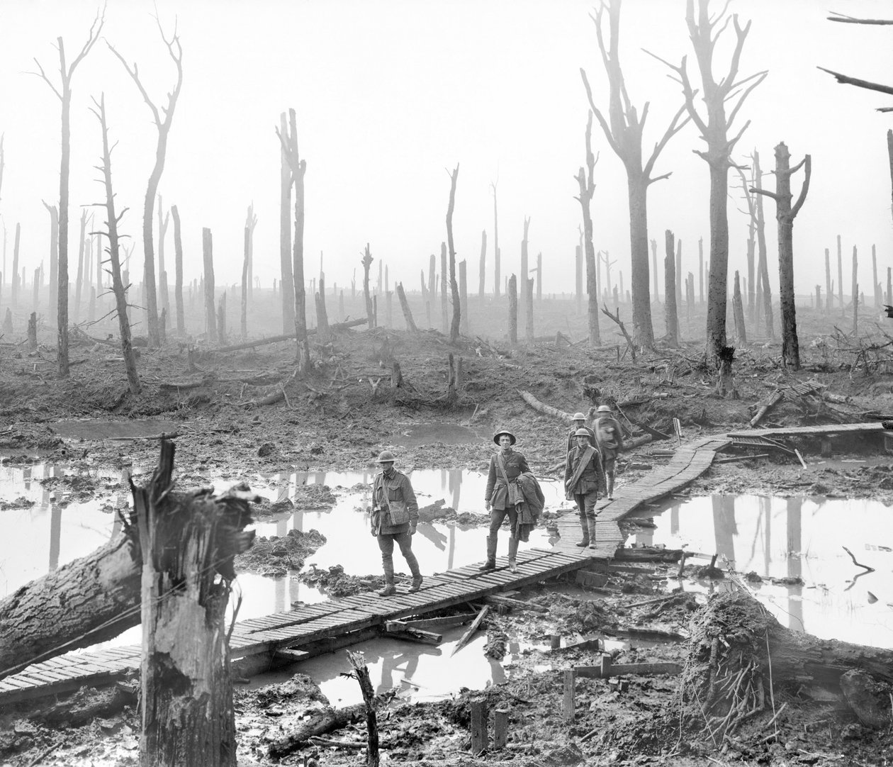 Fem australiere, medlemmer av en feltartilleribrigade, som passerer langs en duckboard-bane over gjørme og vann blant magre nakne trestammer i det ødelagte Chateau Wood, en del av en av kampflyene av Australian Photographer