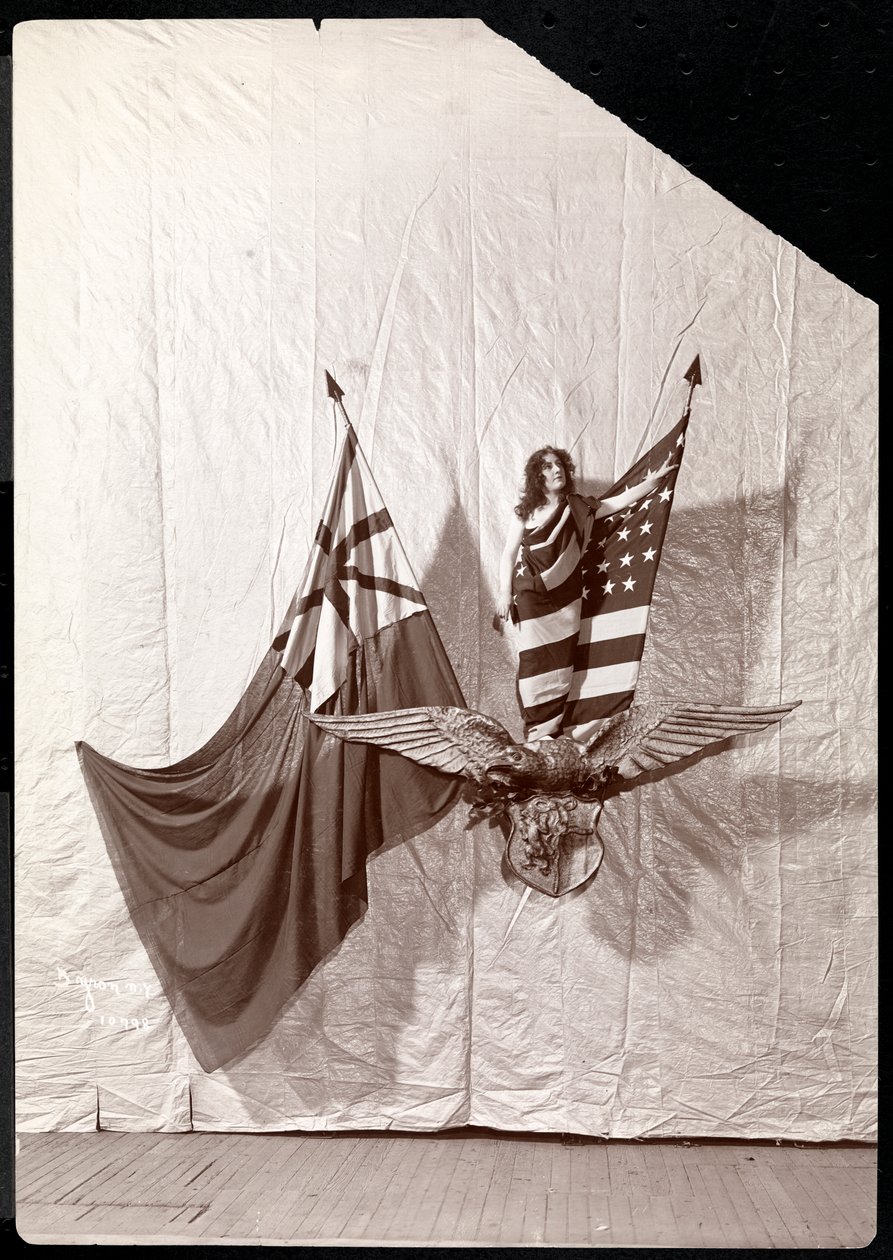 A Living Picture: en modell drapert i det amerikanske flagget som står på toppen av en skulptur av en skallet ørn, 1900 eller 1901 (sølv gelatintrykk) av Byron Company