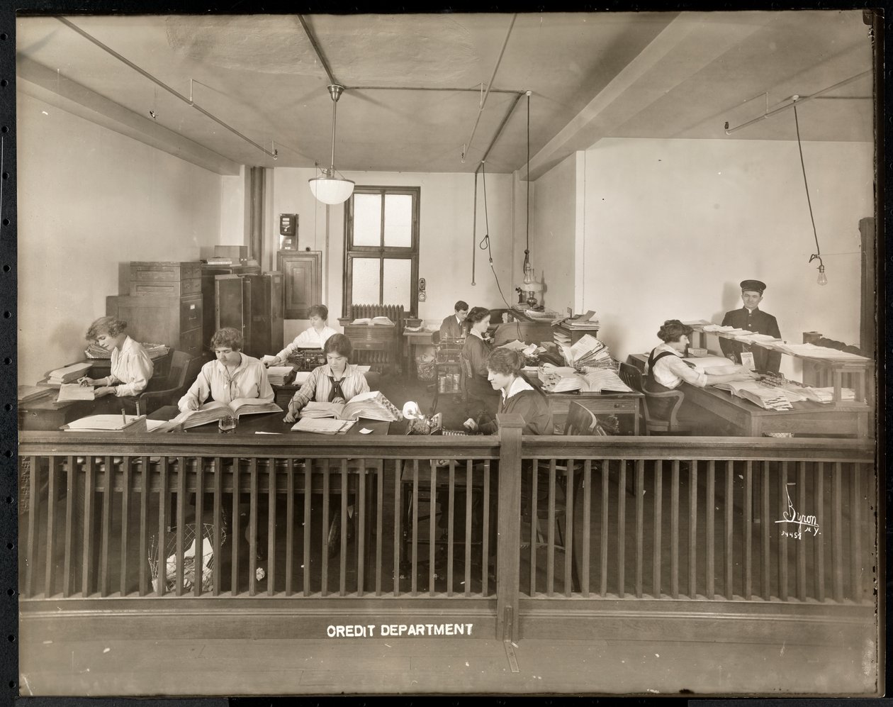 En mann og kvinner som arbeider på kredittkontoret til Mantle Lamp Co. of America, New York, 1915-16 (sølv gelatintrykk) av Byron Company