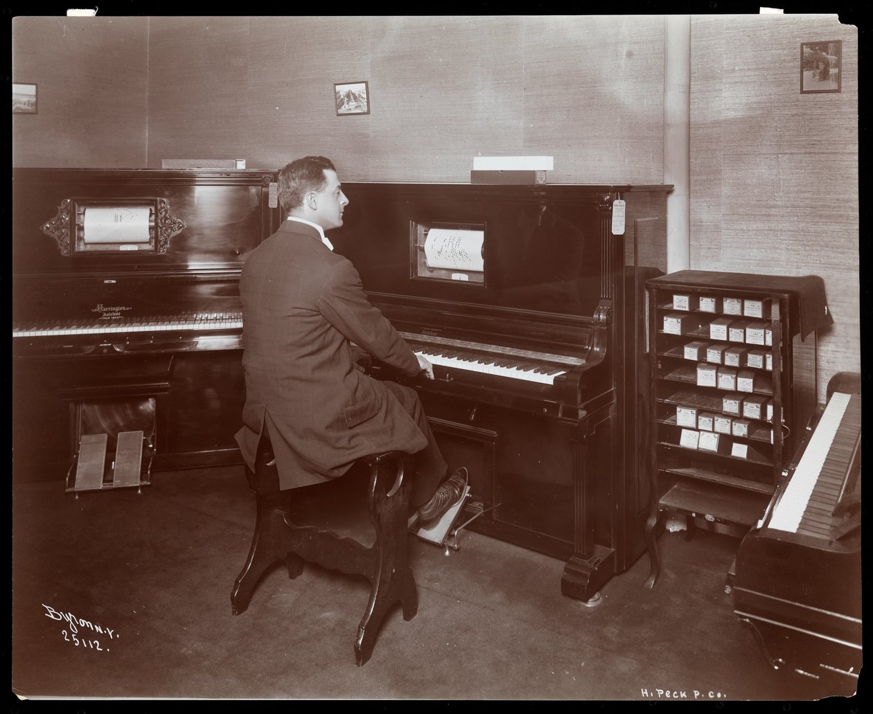 En mann som spiller et pianospiller i et pianoutstillingsrom i New York, 1907 (sølv gelatintrykk) av Byron Company