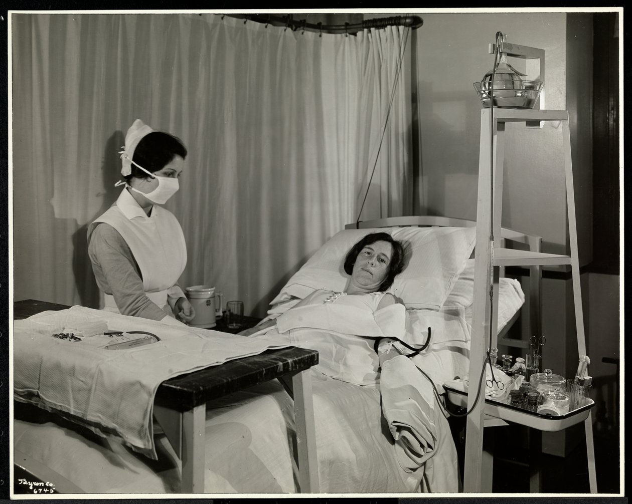 En maskert sykepleier med en pasient på et rom ved Sloane Medical Hospital, Broadway og 168th Street, New York, 1932 (sølv gelatintrykk) av Byron Company