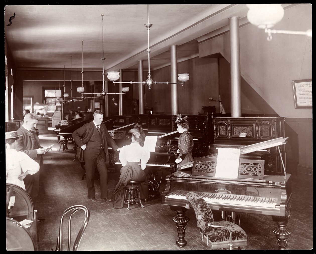 Et utstillingslokale til New England Piano Co., 1895 (sølv gelatintrykk) av Byron Company