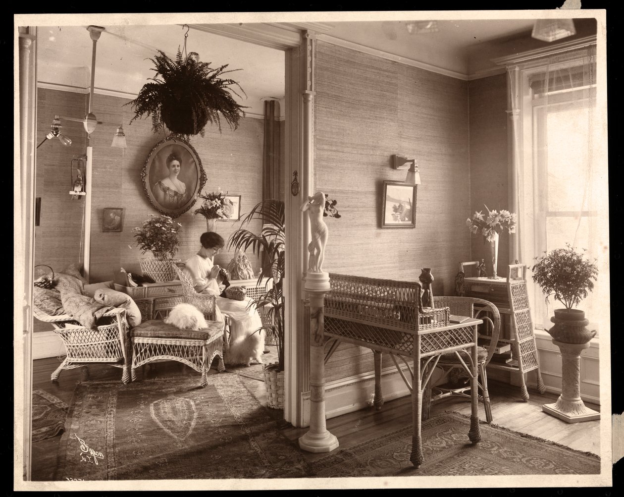 En kvinne som gjør et nålearbeid i en stue, 1914 eller 1915 (sølv gelatintrykk) av Byron Company