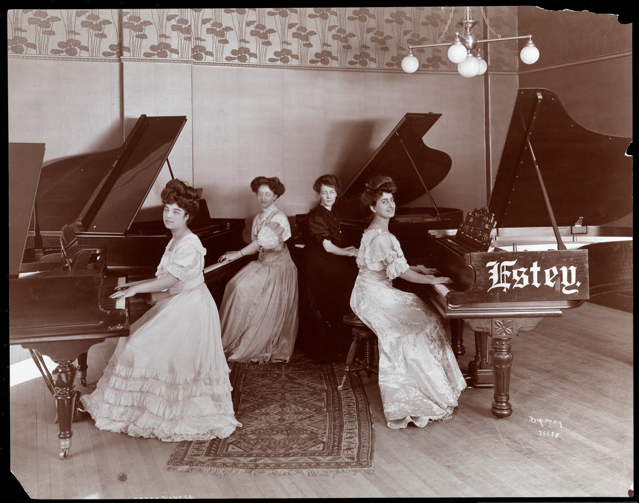 Fire kvinner sittende ved pianoer ved Estey Piano Corporation, 1908 (sølv gelatintrykk) av Byron Company
