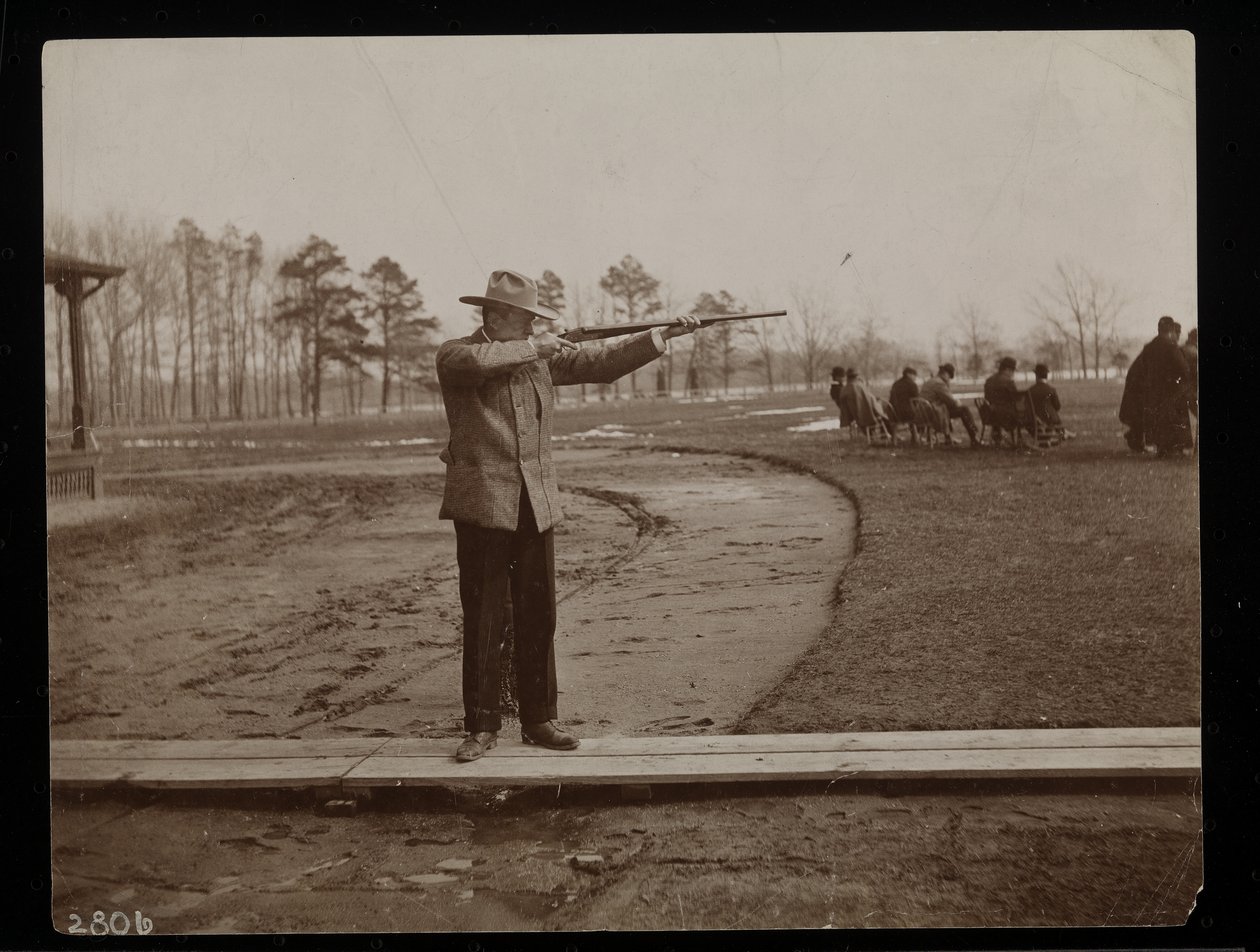 Frank Work sikter en rifle mot et felleskudd, New York, 1896 (sølv gelatintrykk) av Byron Company