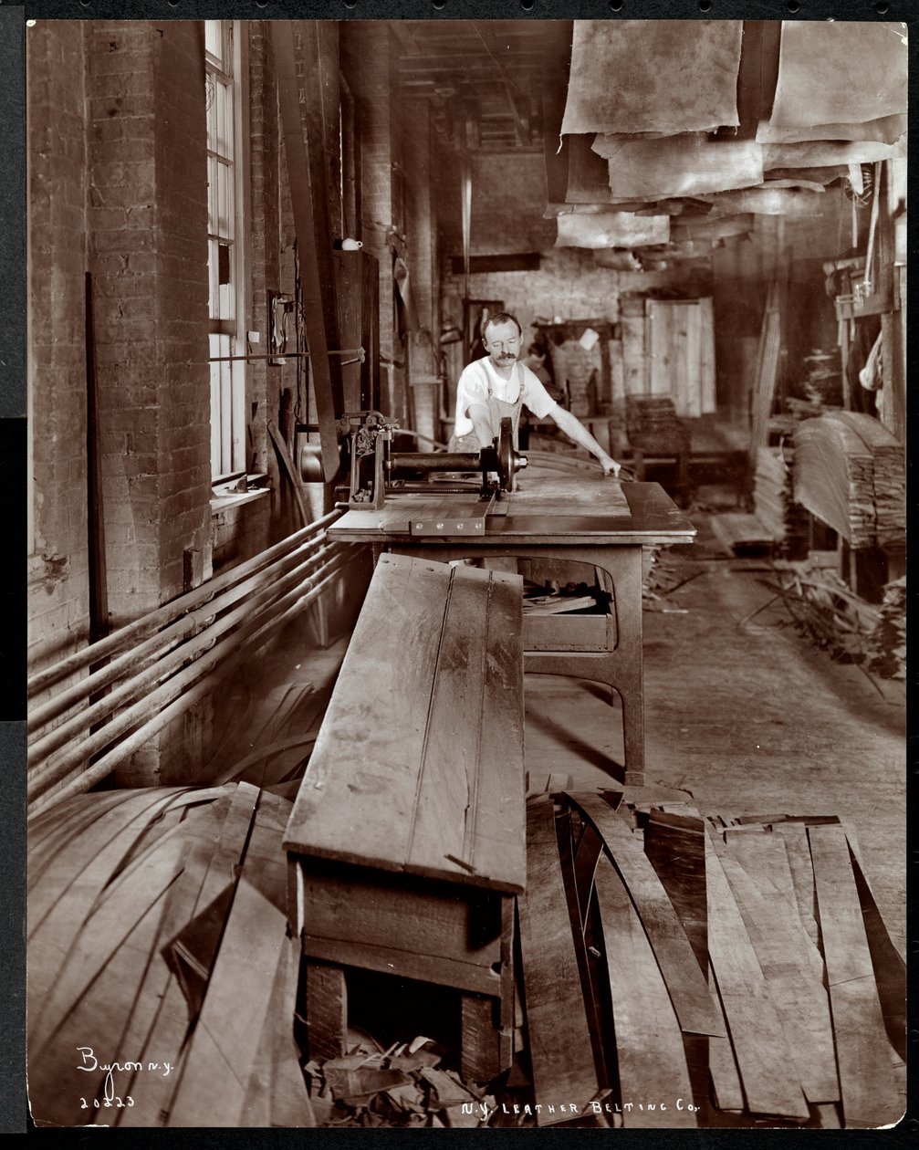 Interiørbilde av en mann som arbeider med skinn ved New York Leather Belting Co., New York, 1905 (sølv gelatintrykk) av Byron Company
