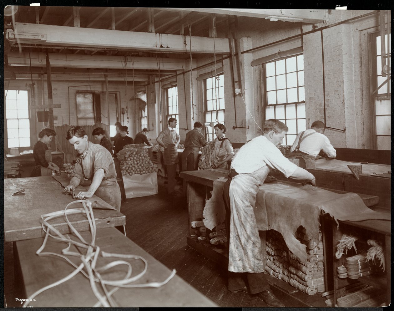 Interiørbilde av menn og kvinner som arbeider med skinn ved New York Leather Belting Co., New York, 1906 (sølv gelatintrykk) av Byron Company