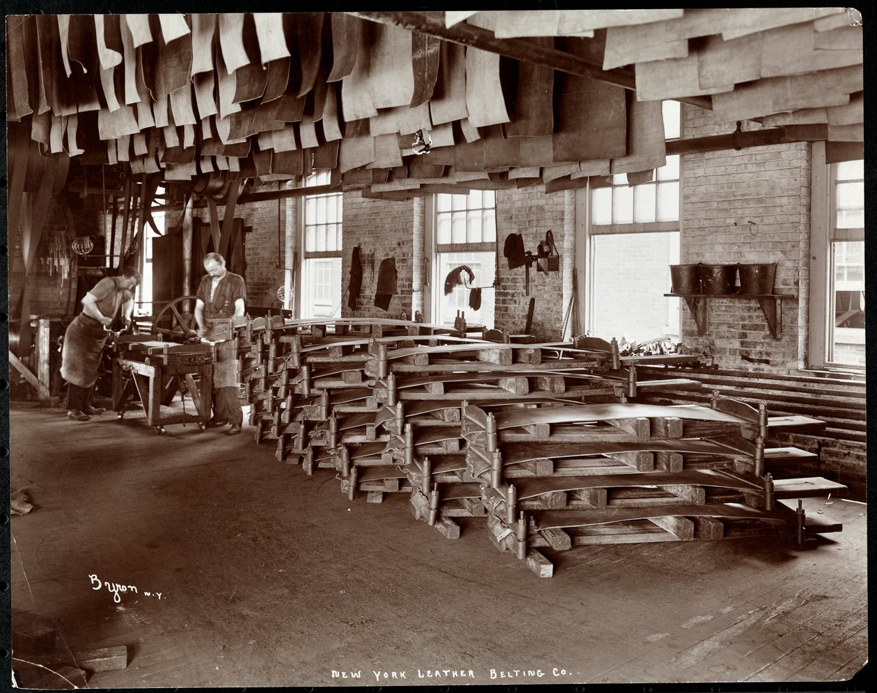 Interiørbilde av to menn som arbeider med skinn ved New York Leather Belting Co., New York, 1905 (sølv gelatintrykk) av Byron Company