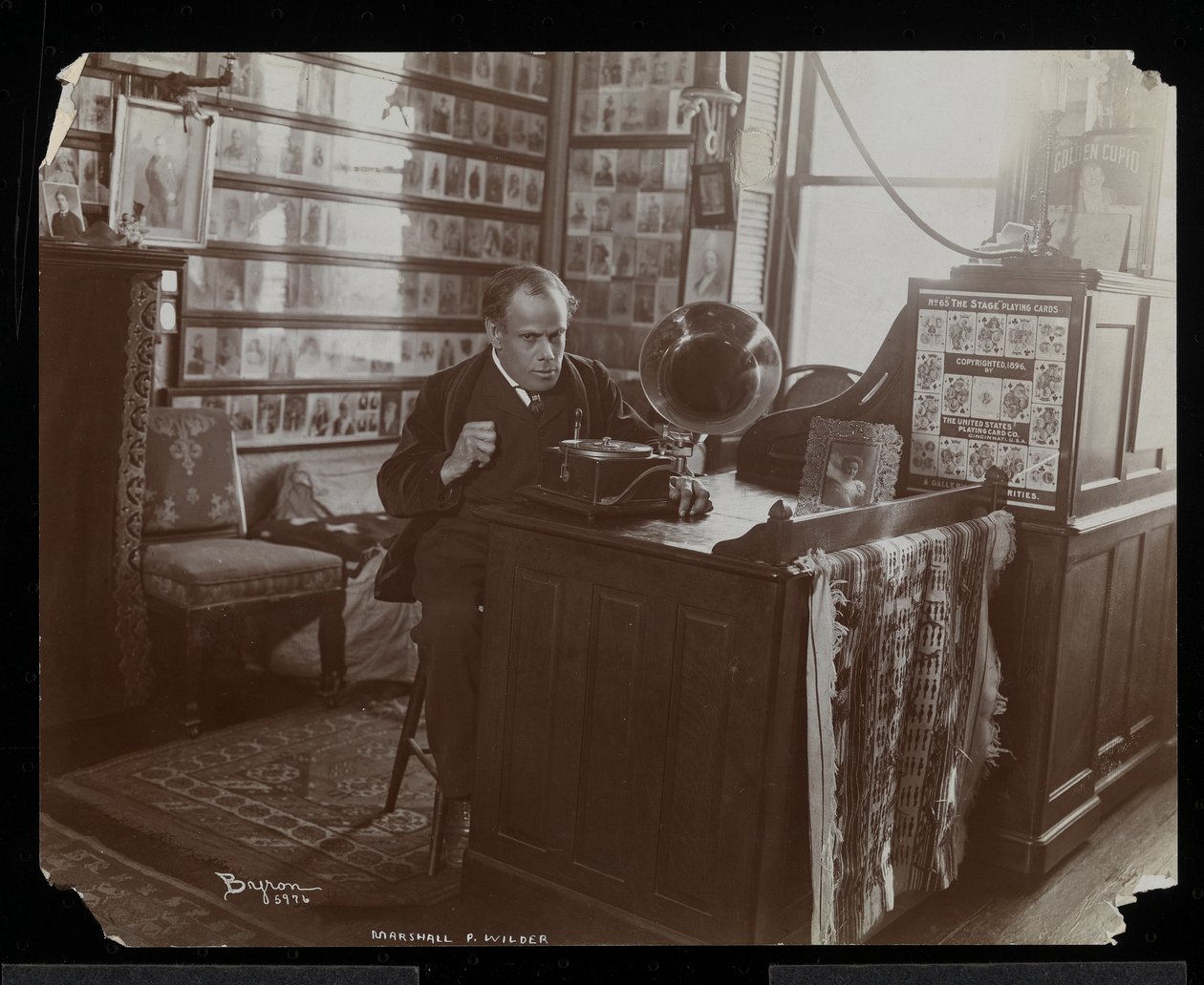 Marshall P. Wilder lytter til en plate på en victrola på kontoret sitt, 1898-99 (sølv gelatintrykk) av Byron Company