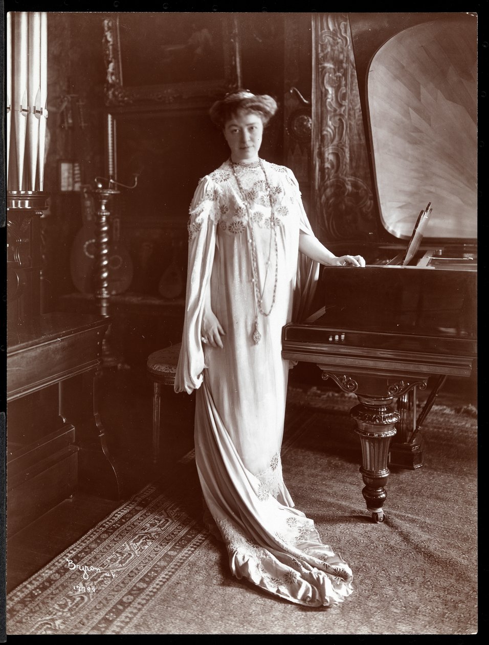 Portrett av fru I. M. Clark stående ved et piano, 1904 (sølv gelatintrykk) av Byron Company