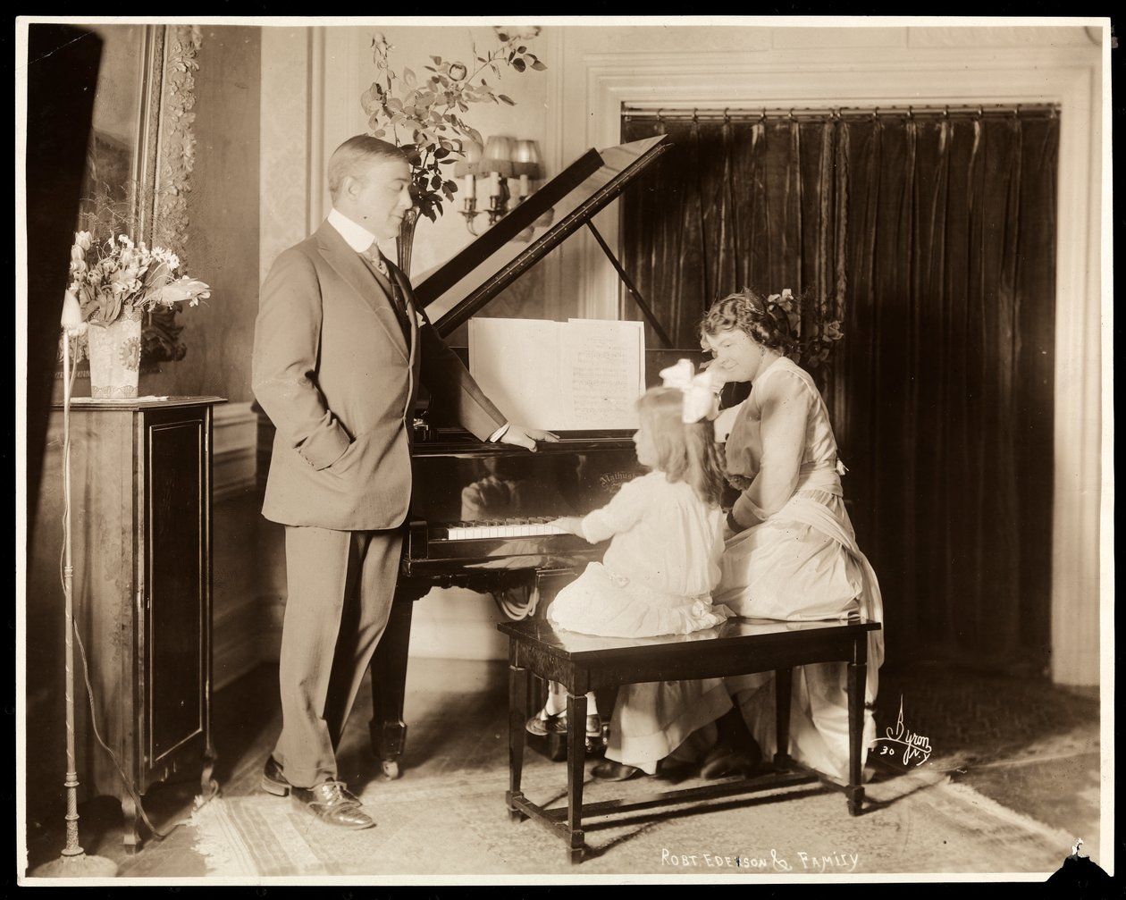 Robert Edeson, hans kone og datter ved pianoet, ca. 1915 (sølv gelatintrykk) av Byron Company