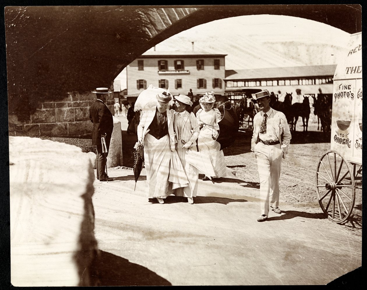 Tre kvinner og en mann går ved Narragansett Pier med omreisende fotografvogn, Rhode Island, 1891 (sølvgelatintrykk) av Byron Company