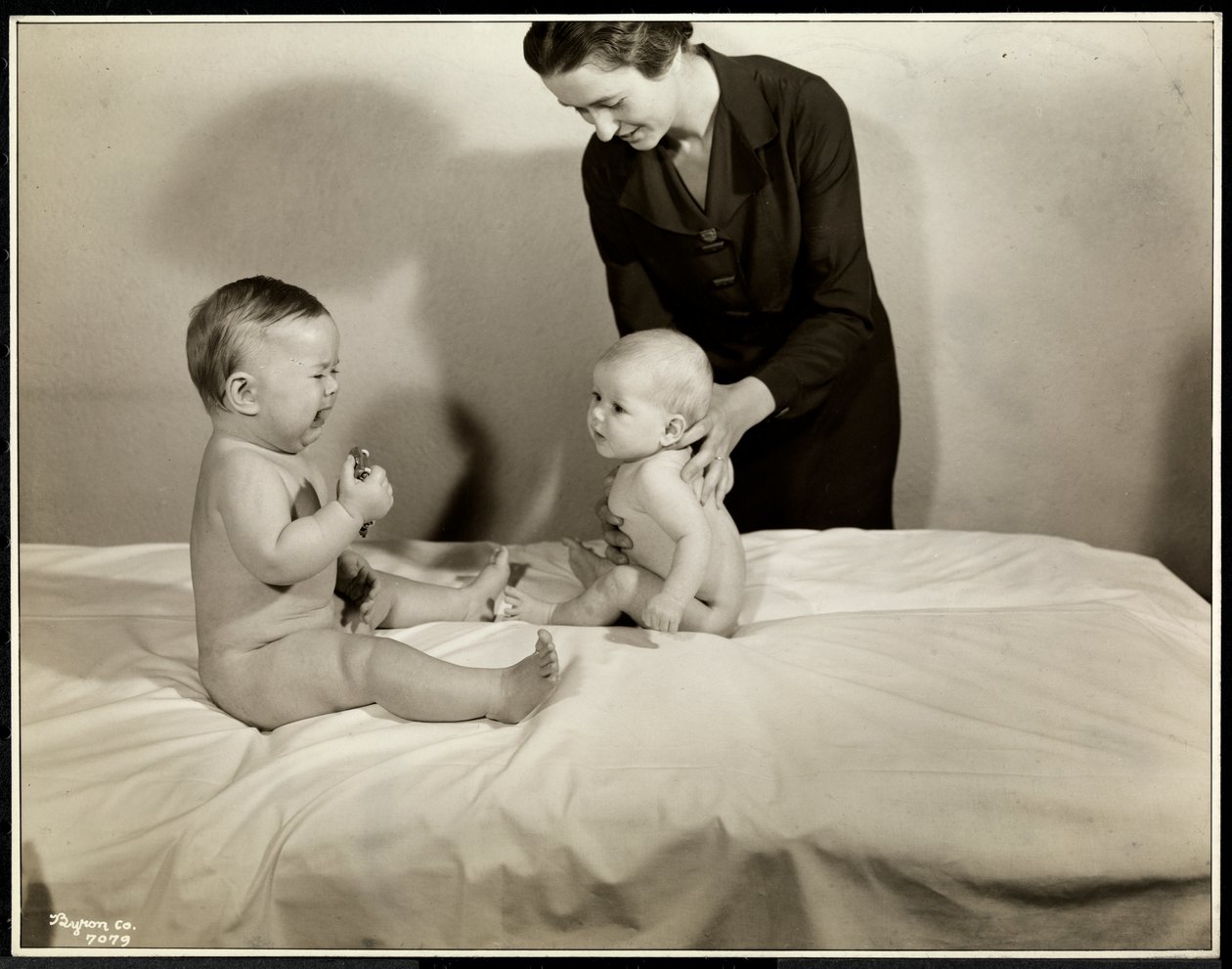 To babyer som sitter oppe i sengen, den ene blir støttet av en sykepleier, den andre holder en lekebil og gråter på Maternity Center Association i 70th Street East River, New York, 1935 (sølv gelatintrykk av Byron Company