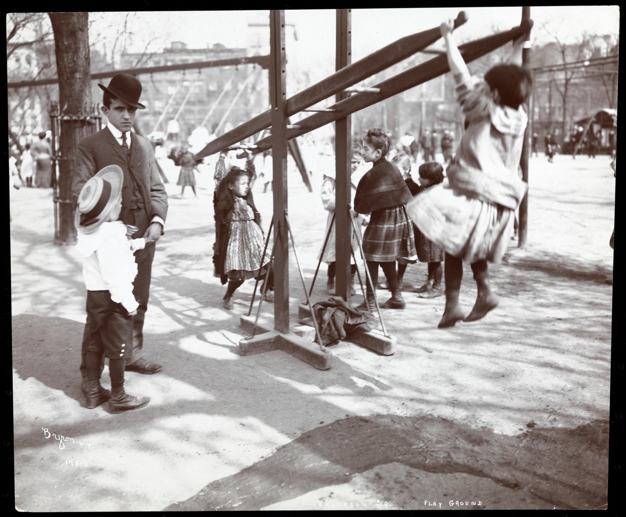 Utsikt over en mann som fører tilsyn med barn som leker på lekeapparater i Tompkins Square Park, på Arbor Day, New York, 1904 (sølv gelatintrykk) av Byron Company