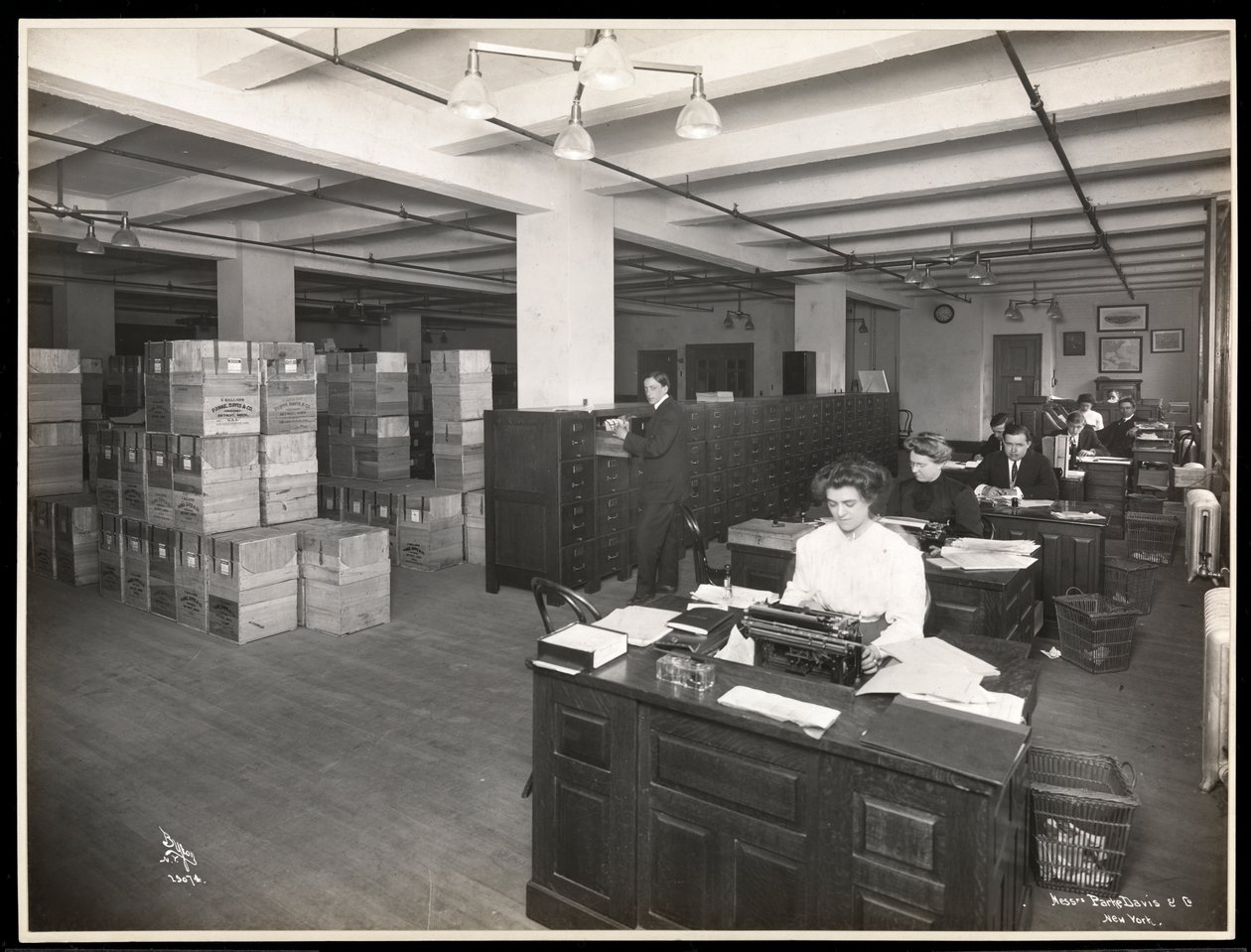 Utsikt over menn og kvinner ved pulter i det som ser ut til å være et fraktrom i Parke, Davis und Co., chemists, Hudson und Vestry Streets, New York, 1910 (sølvgelatintrykk) av Byron Company