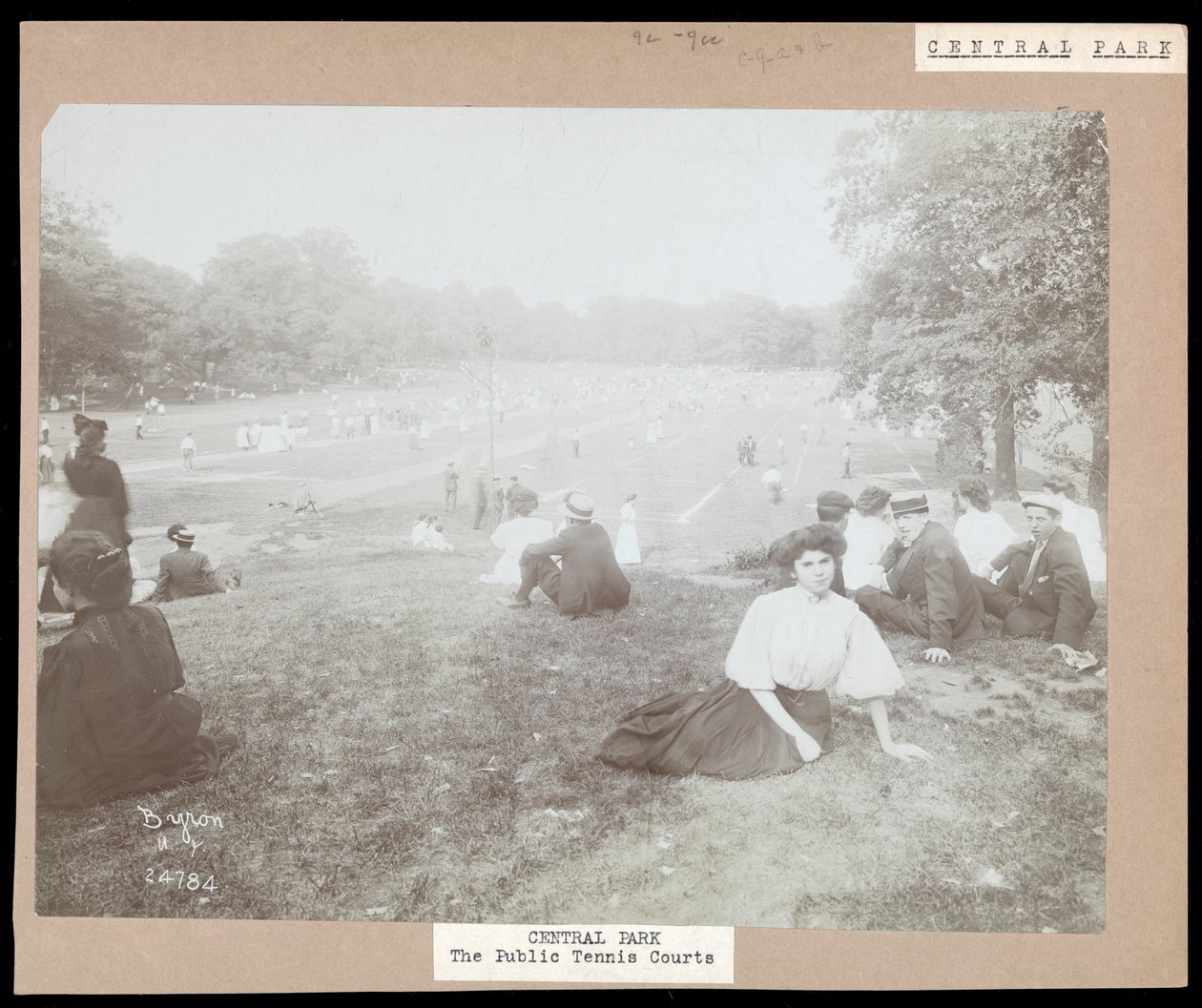 Utsikt over menn og kvinner som sitter på gresset og ser på plentennis i Central Park, New York, ca. 1917 (sølv gelatintrykk) av Byron Company