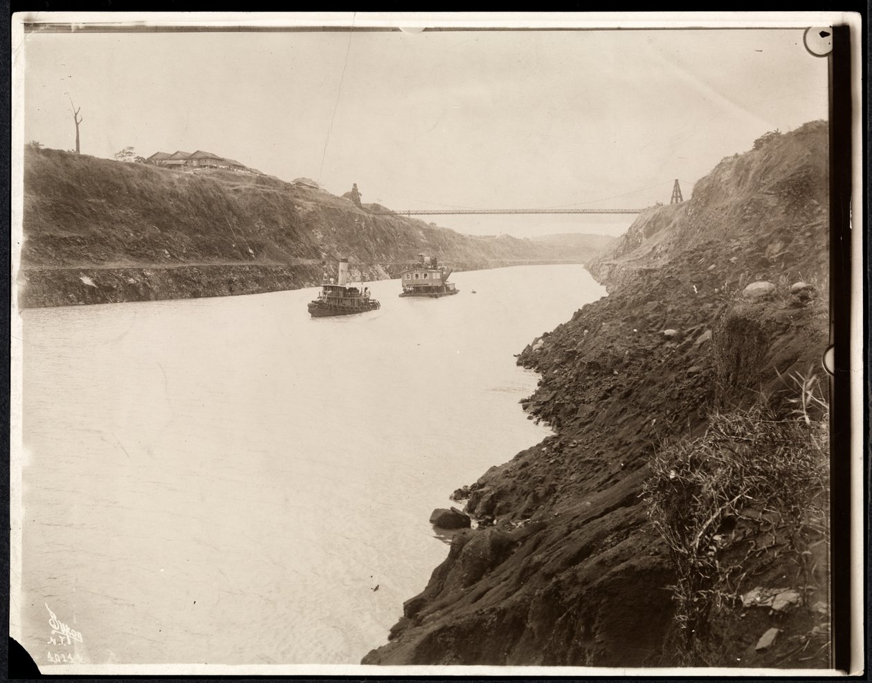 Utsikt over to båter i Panamakanalen under konstruksjonen med en hengebro utover, 1913 (sølvgelatintrykk) av Byron Company