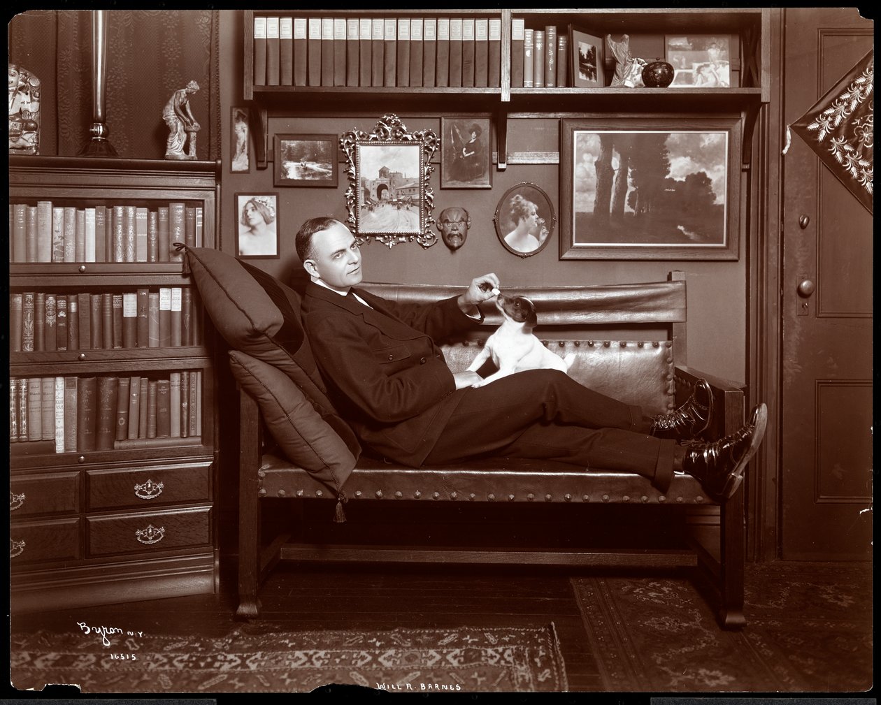 Will R. Barnes satt tilbakelent på en sofa med en hund i bibliotekstudioet hans, 1903 (sølv gelatintrykk) av Byron Company