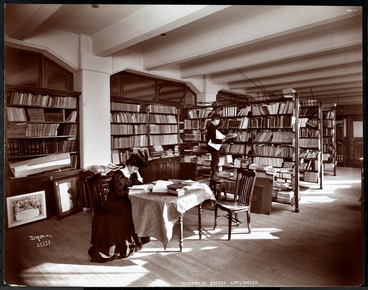 Kvinne og en ung mann i et bibliotek i Museum of Safety Appliances ved American Institute of Social Service, New York, 1907 (sølvgelatintrykk) av Byron Company