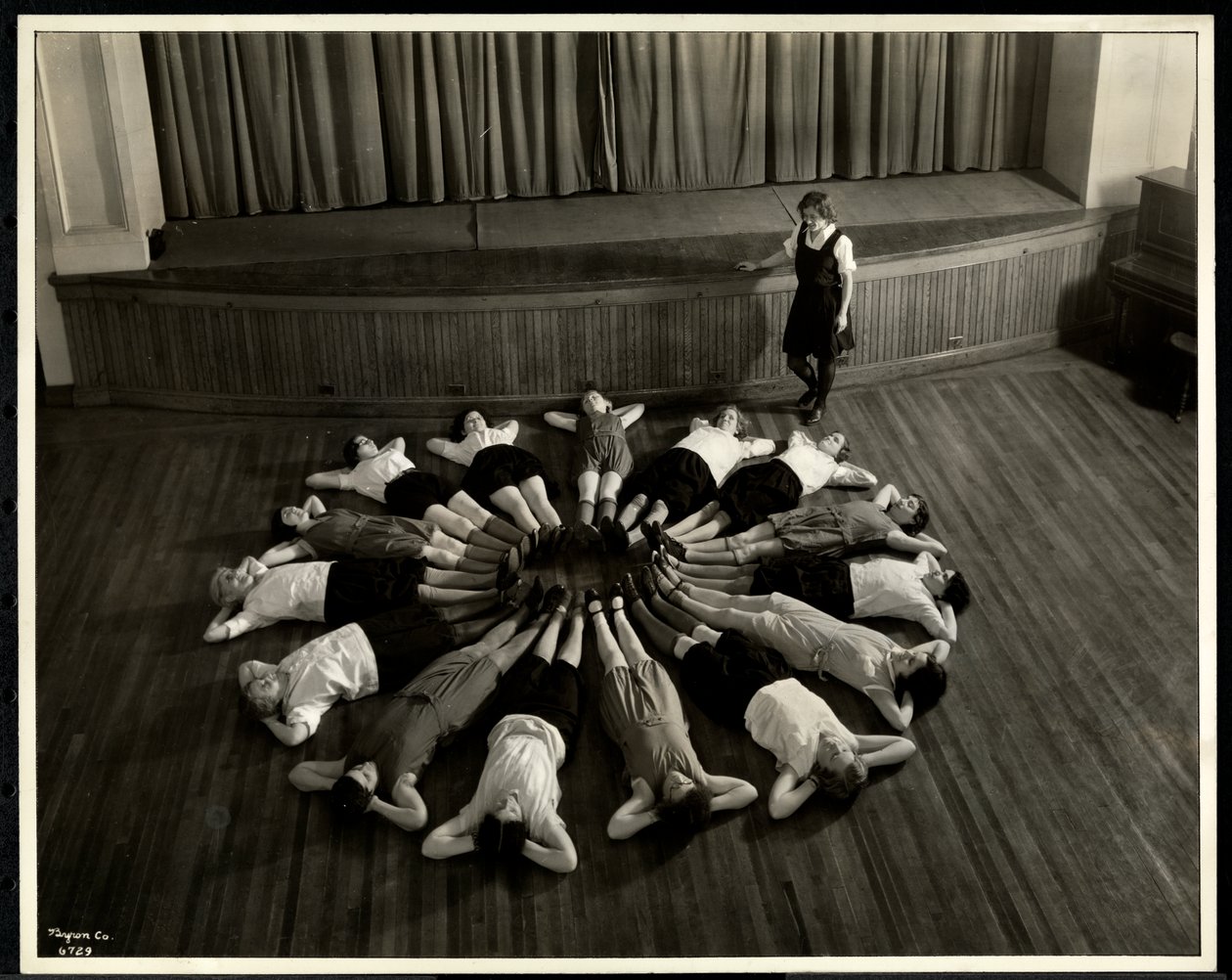 Unge blinde kvinner som ligger i et stjerneskuddsmønster på gulvet i gymsalen ved New York Association for the Blind, 111 East 59th Street, New York, 1933 (sølv gelatintrykk) av Byron Company
