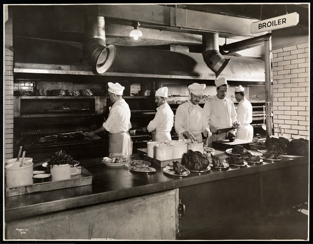 Kokker ved slaktekyllingen på kjøkkenet på Hotel Commodore, 1919 (sølv gelatintrykk) av Byron Company