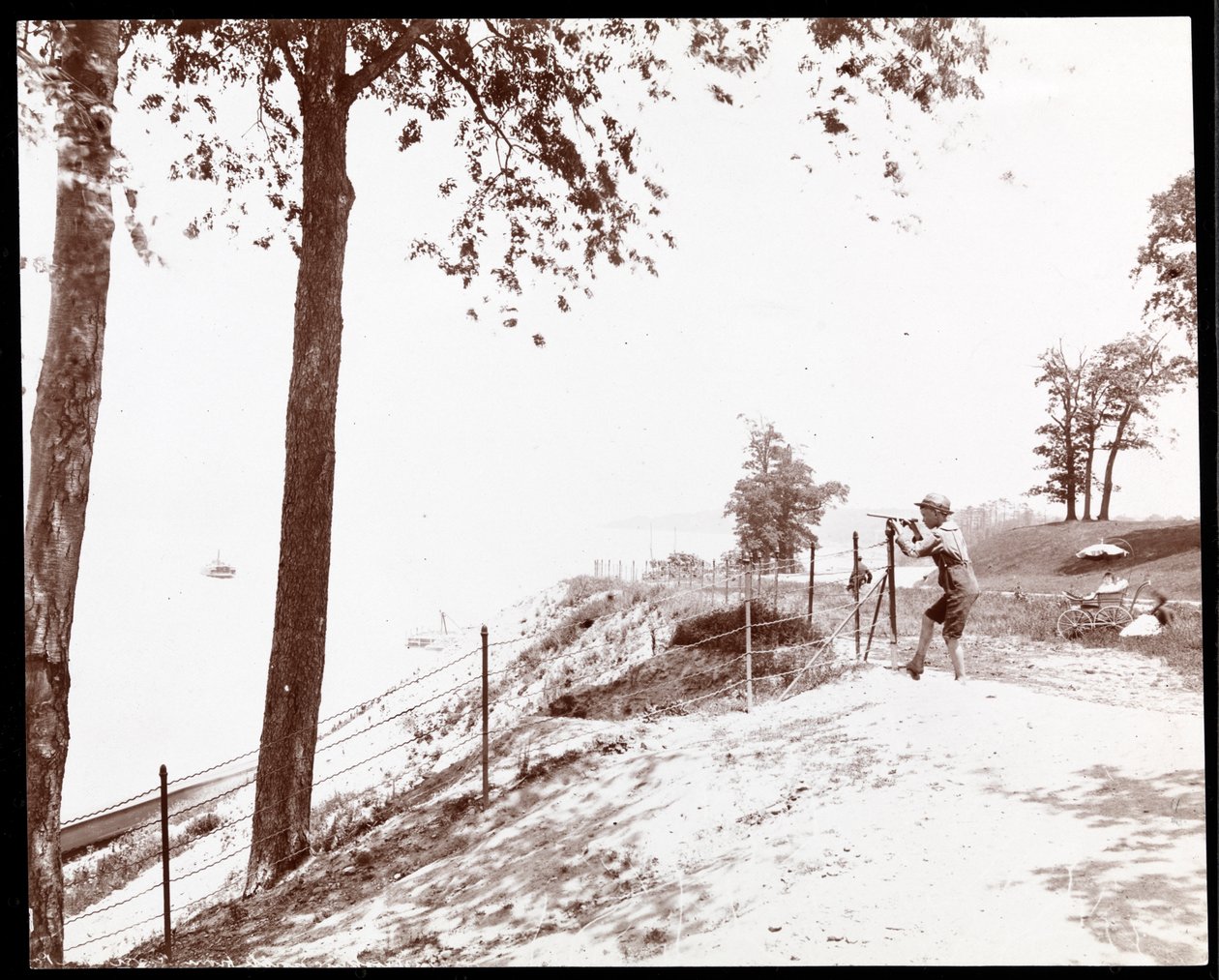 Utsikt over en gutt med kikkert som ser mot Hudson River fra Riverside Park, New York (sølv gelatintrykk) av Byron Company