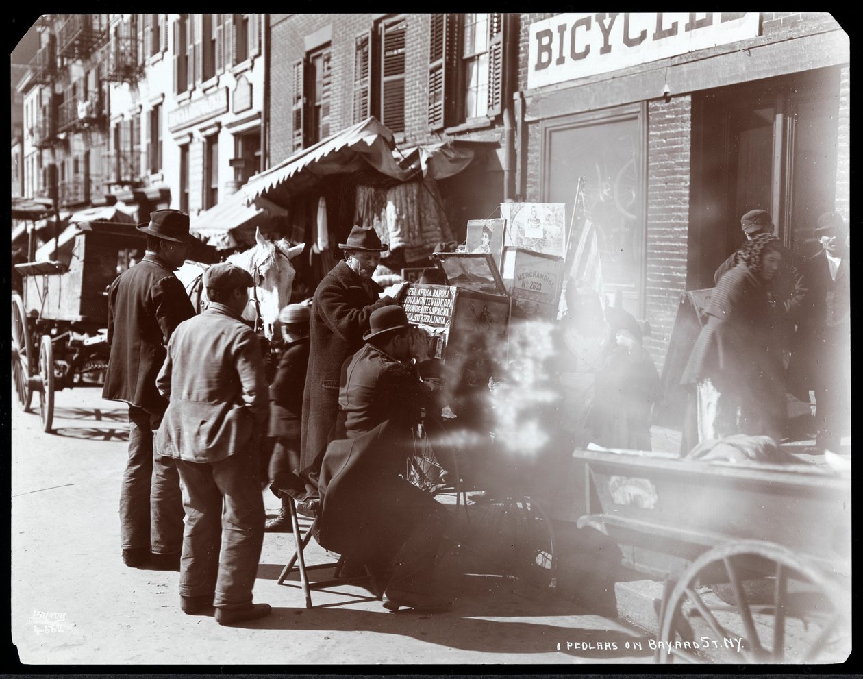Utsikt over gateselgere, inkludert en som viser fotografisk utsikt over eksotiske steder i en utsiktsboks, på Bayard Street, New York, 1898 (sølv gelatintrykk) av Byron Company
