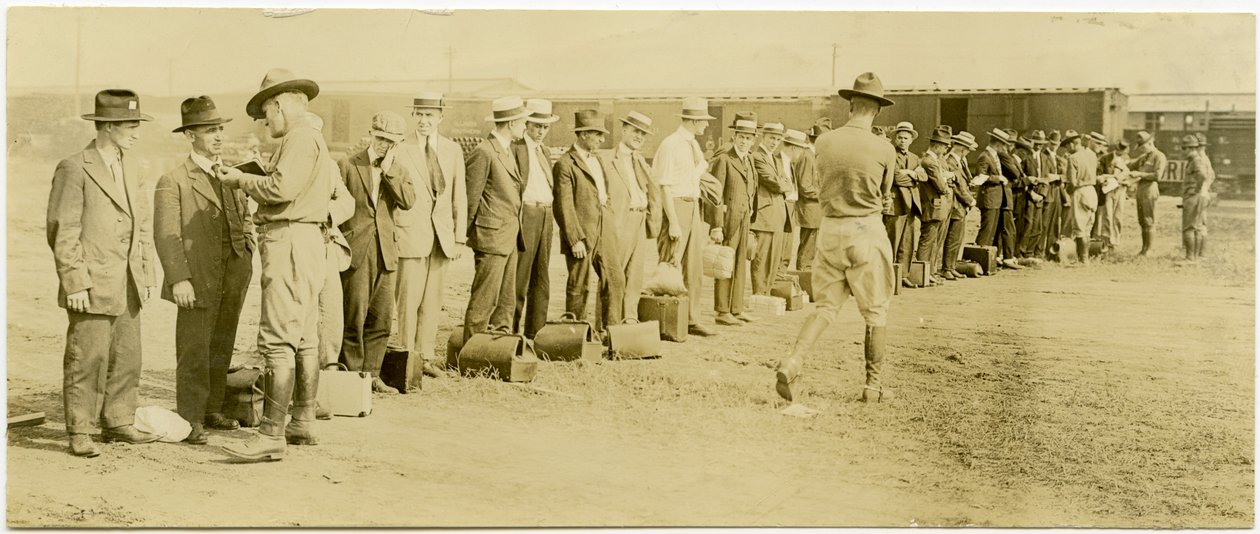Horisontalt, sepia -fotografi som viser en gruppe menn i sivile klær, hvorav mange har bagasje, som står i kø. Uniformerte soldater går langs linjen og snakker individuelt med mennene. Jernbanespor og togvogner kan sees i ba av Carl Michel