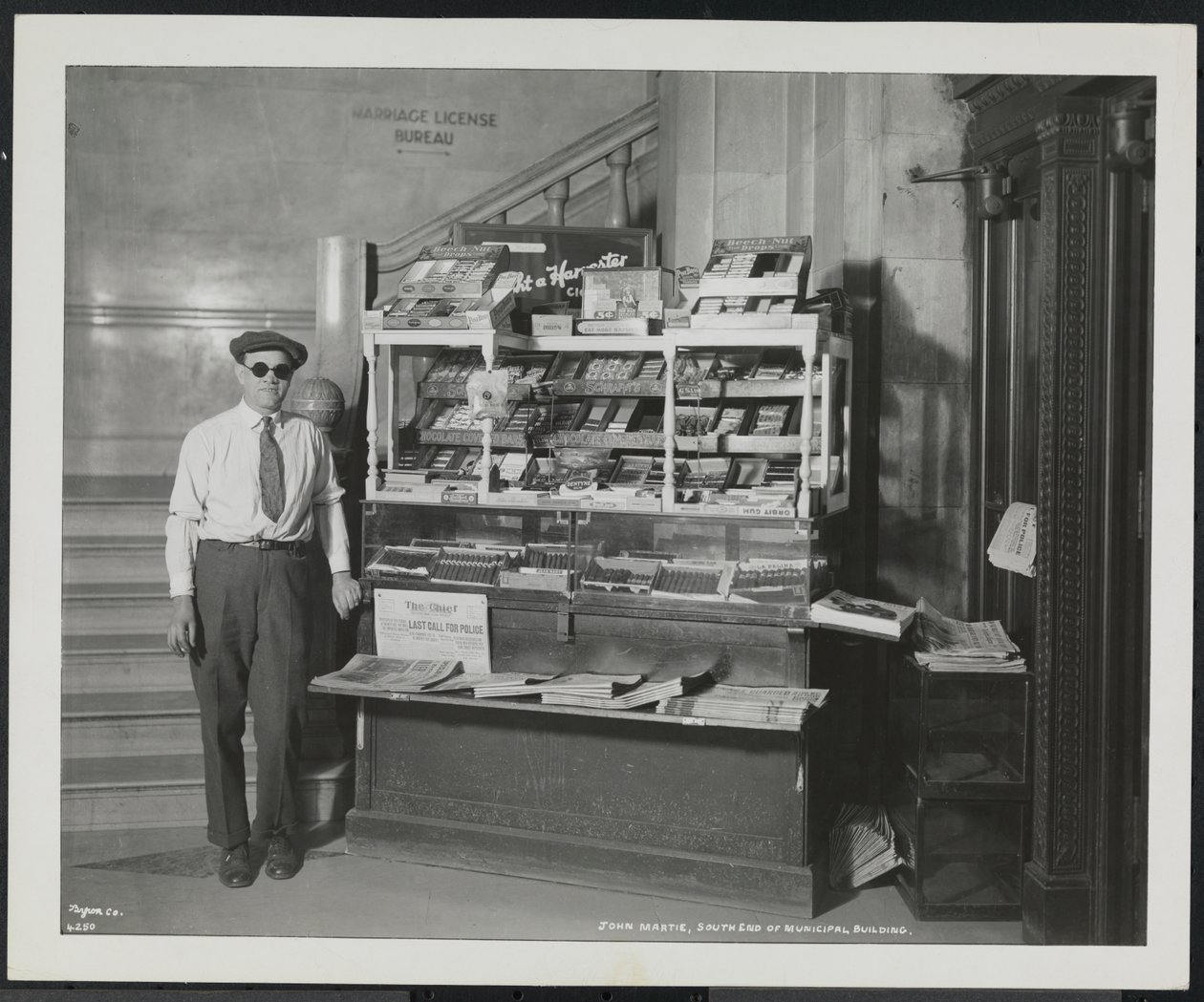 Blind nyhetsforhandler, John Martie, på standen hans i sørenden av kommunalbygningen, New York av Company Byron