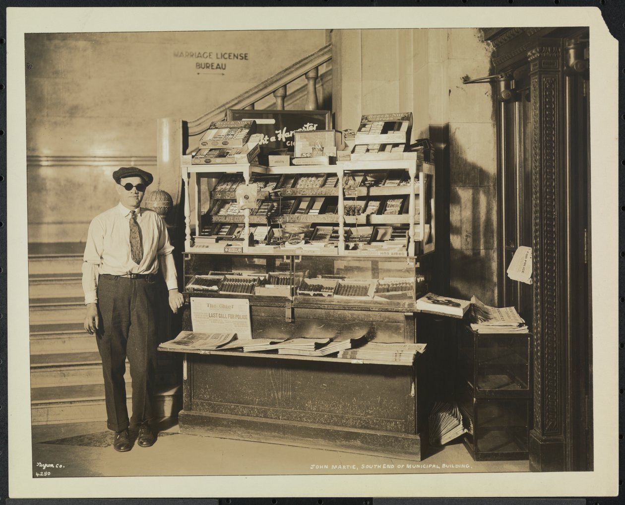 Blind nyhetsforhandler, John Martie, på standen hans i sørenden av kommunalbygningen, New York av Company Byron