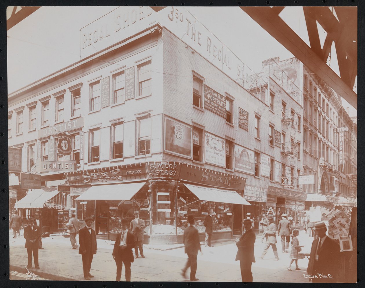 Det sørvestlige hjørnet av 14th Street og 3rd Avenue som viser Star Candies-butikken, en tannlege, Regal Shoe-butikken og Empire Film Co. med fotgjengere, reklametavler og en bjelke fra 3rd Avenue elevated railroad synlig, ca. 1905 (b/ w bilde) av Company Byron