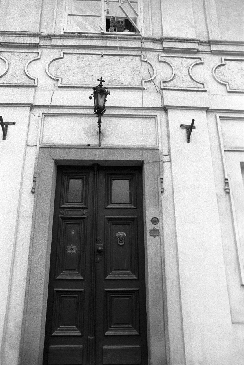 Jiri Mucha senker en nøkkel på en snor slik at en besøkende kan åpne dørene til huset sitt i Hradcany, Praha av Czech Photographer