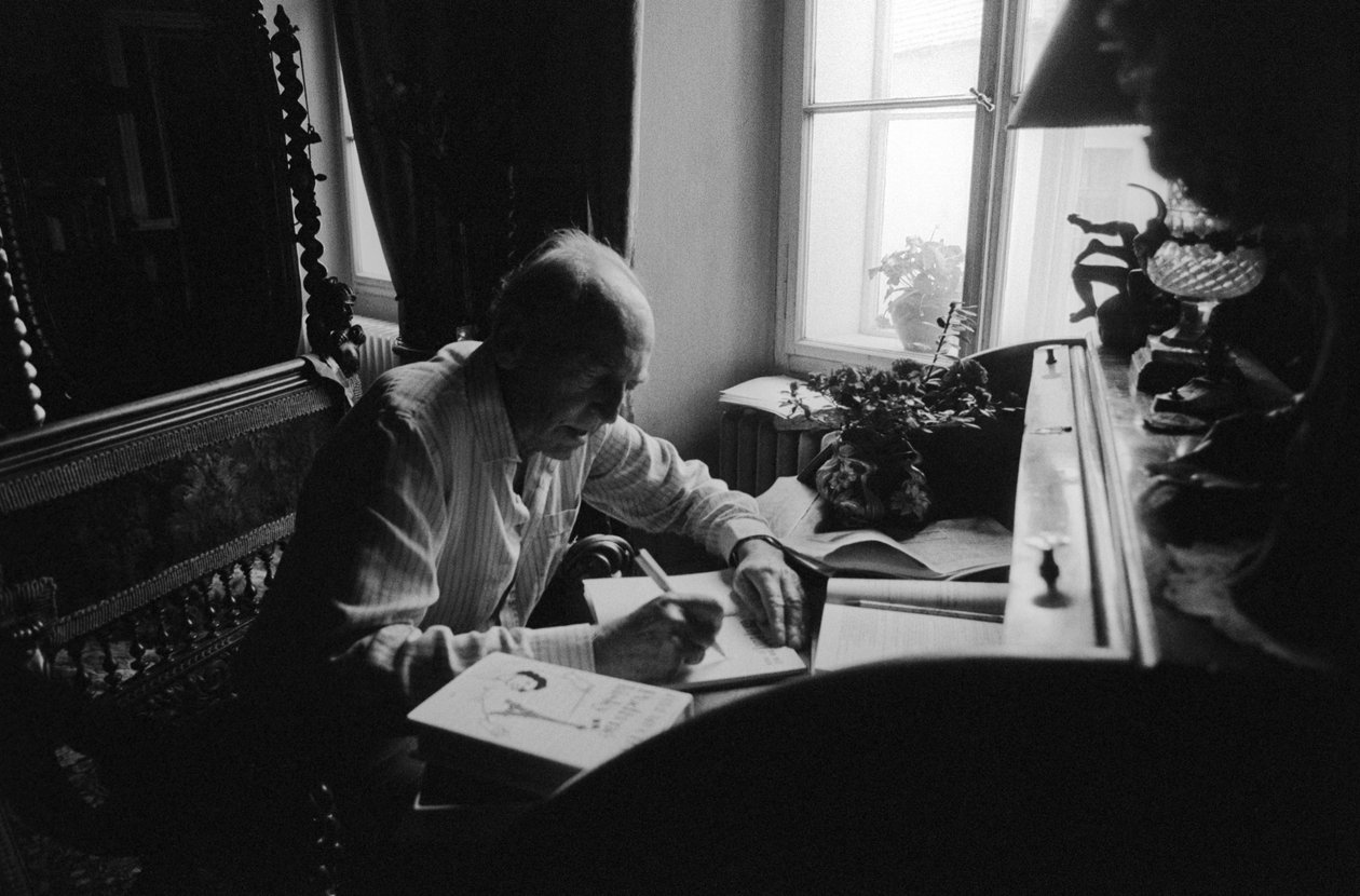 Jiri Mucha sitter ved skrivebordet sitt i huset sitt i Hradcany, Praha av Czech Photographer