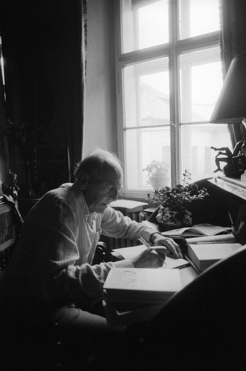 Jiri Mucha sitter ved skrivebordet sitt i huset sitt i Hradcany, Praha av Czech Photographer