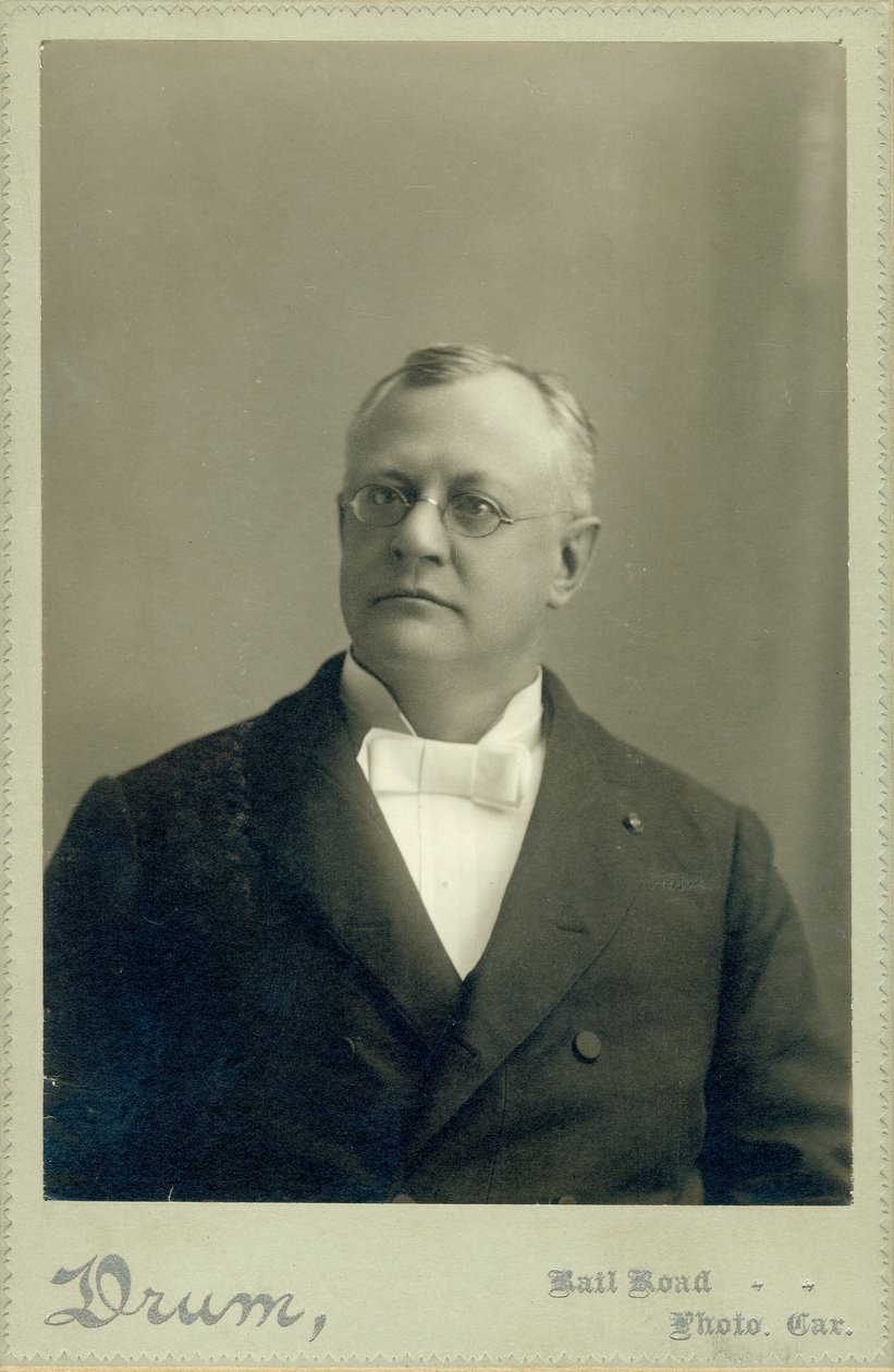 Brystportrett av Clarence W. Backus iført dress av Drum