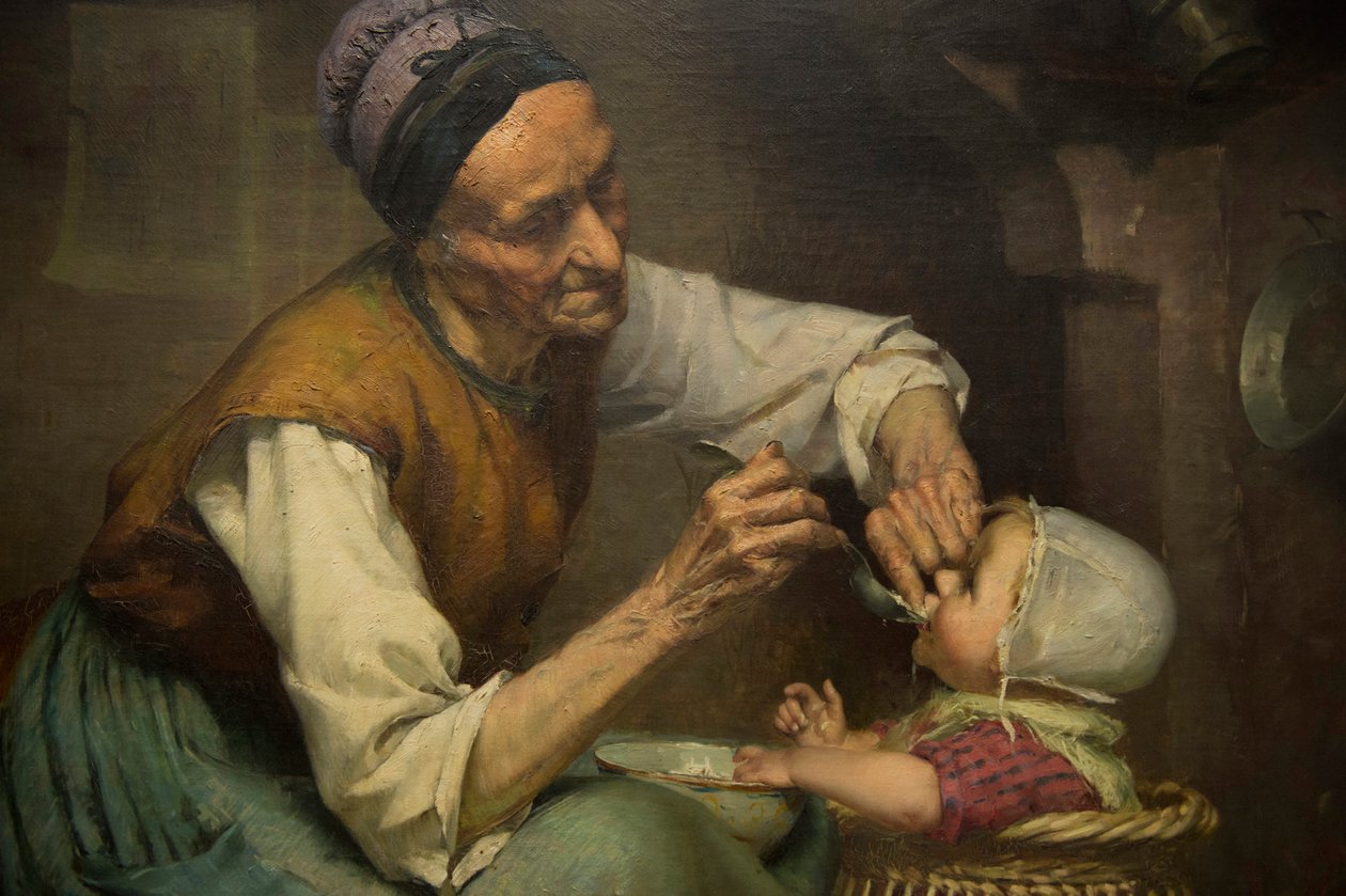 En gammel kvinne mater barnebarnet sitt holdt i en flettet barnerullator, av Edouard Jerome Paupion av Edouard Jerome Paupion