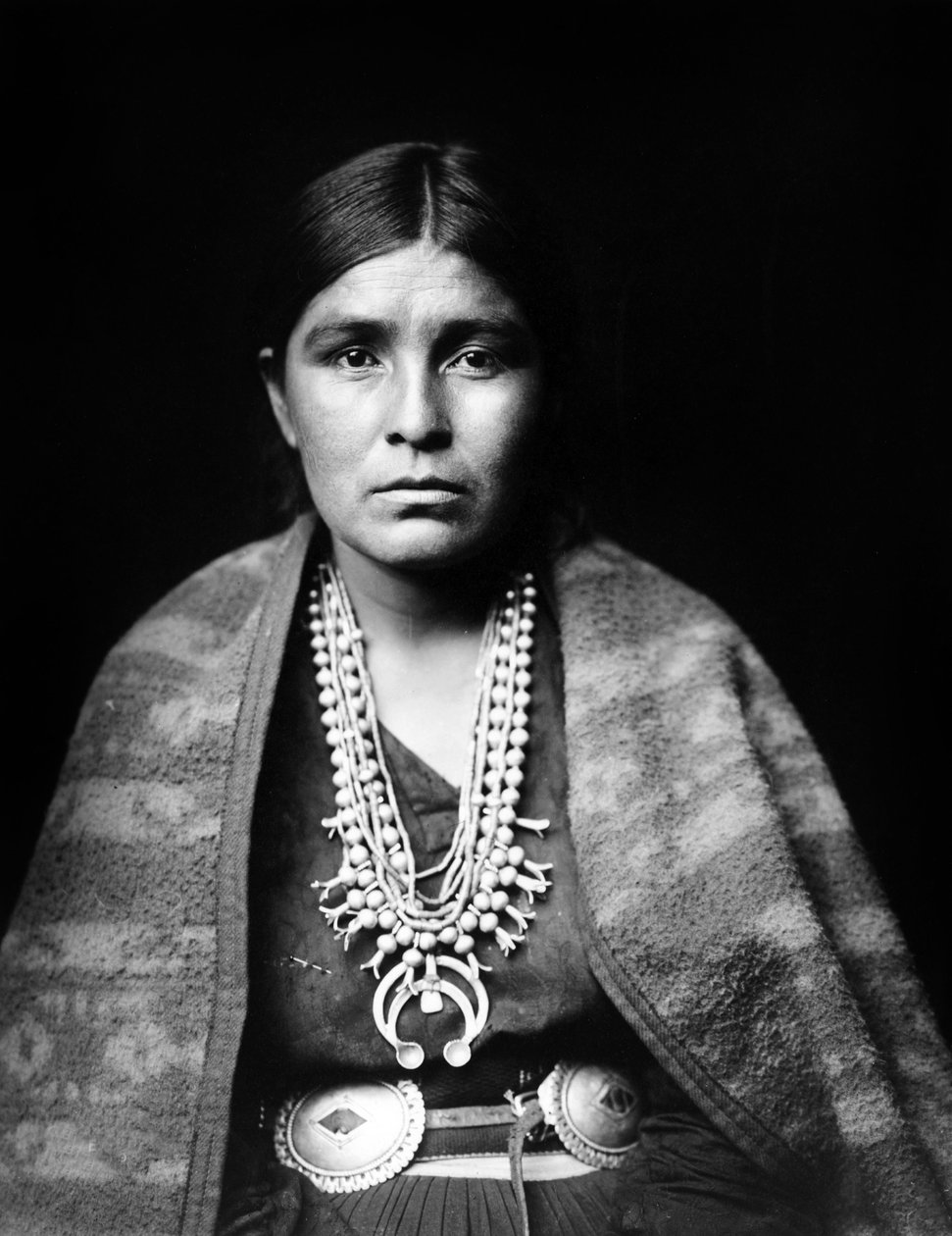 Navajo-kvinne iført sølvkjede med squashblomster, concho-belte, teppe drapert over skuldrene, ca. 1904, foto Edward S. Curtis av Edward Sheriff Curtis
