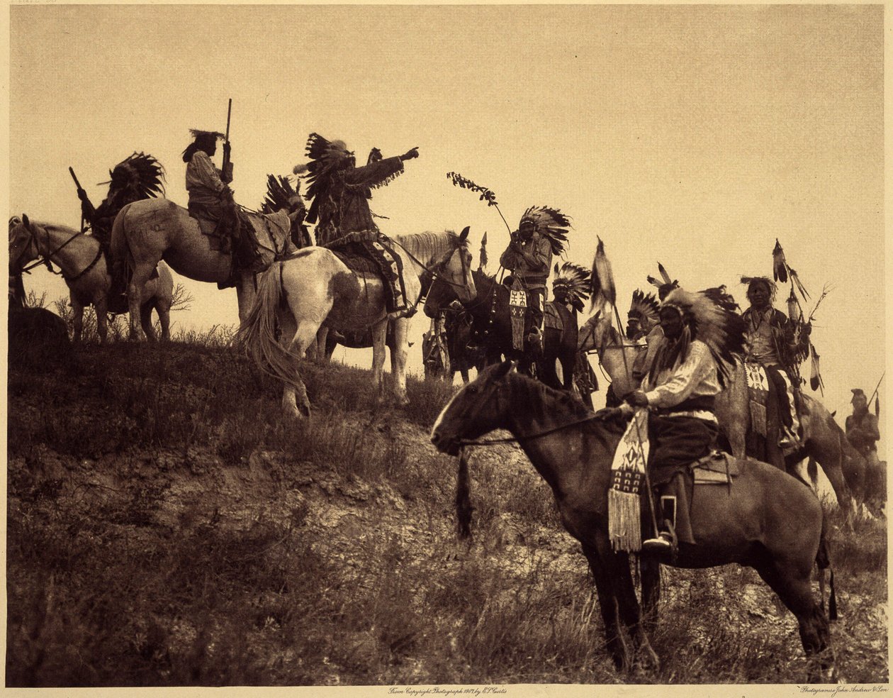 Planlegger et raid. Indianerne, i sine imponerende typiske kostymer, samles i ekstremt pittoreske grupper. Dette er en tropp fra Sioux Ogalala (Oglala), på en høyde med utsikt over Wounded Knee Valley i Pine Ridge Reserve, South Dakota. Foto tak av Edward Sheriff Curtis