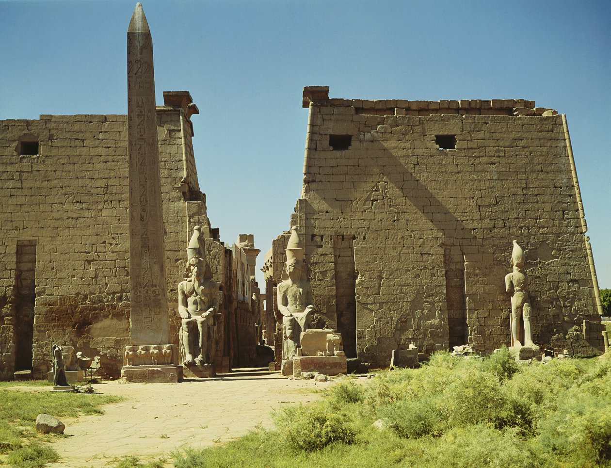 Fasade og første pylon med to sittende statuer av Ramesses II og den gjenværende obelisken av Egyptian 19th Dynasty