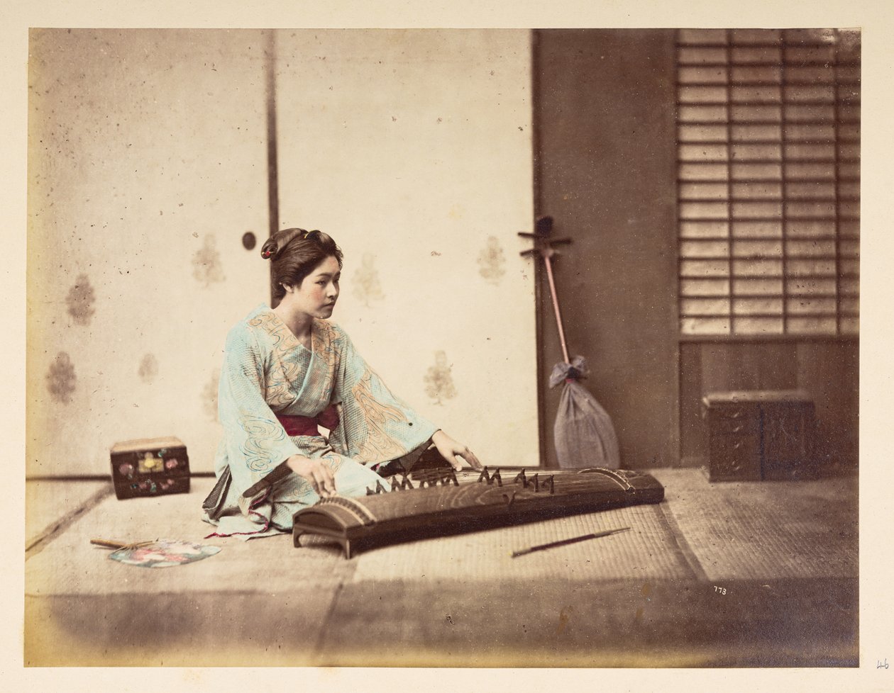 Syngende jenter [Japan], Studioportrett av en ung japansk kvinne som sitter på en tatamimatte og spiller et strengeinstrument,  Fotograf: Ukjent  Lucas Collection: Fotografisk oversikt over verdensturneen til Charles James og Morton P, Lucas av English Photographer